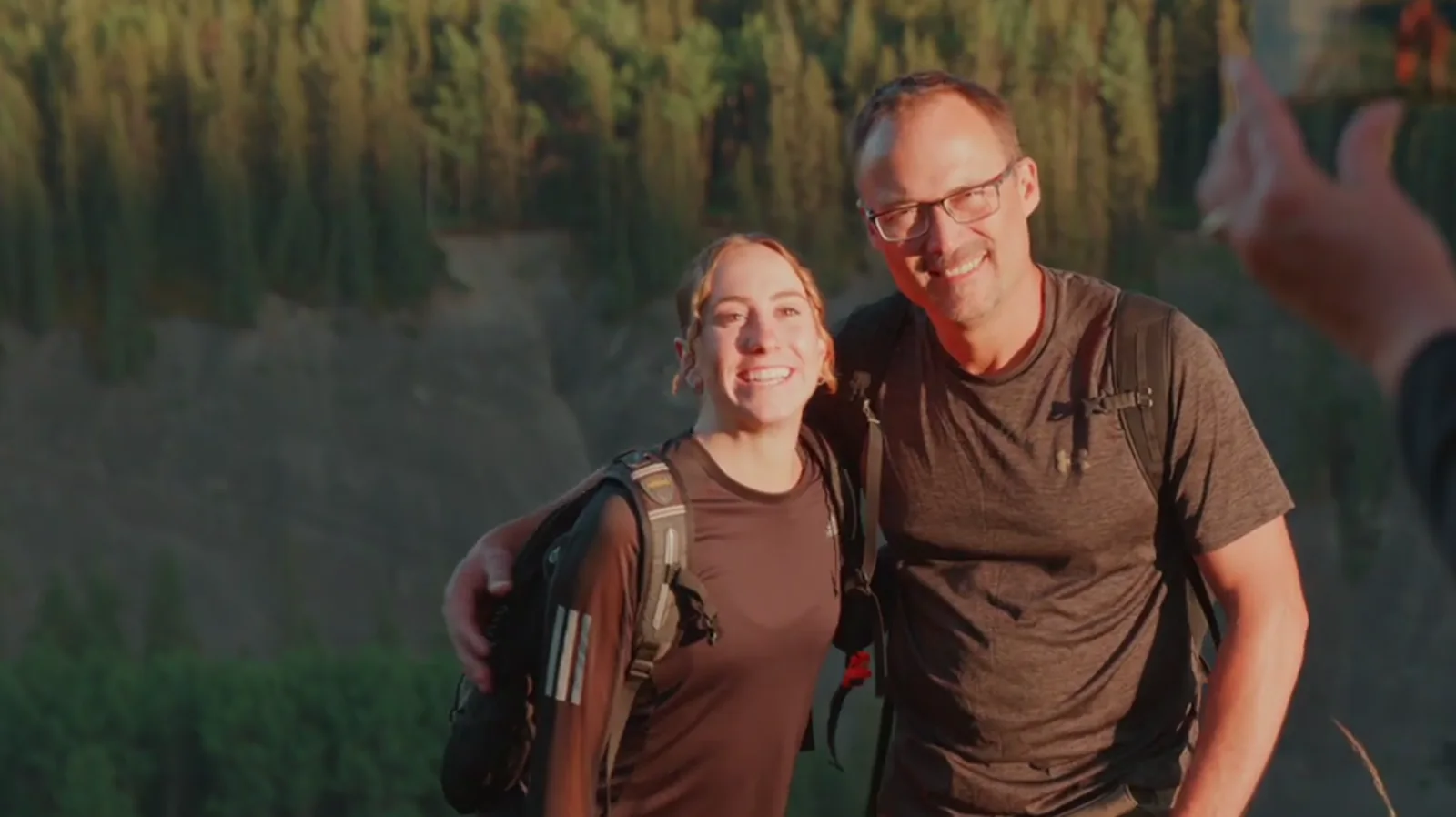 A father and his adult daughter smiling together at golden hour