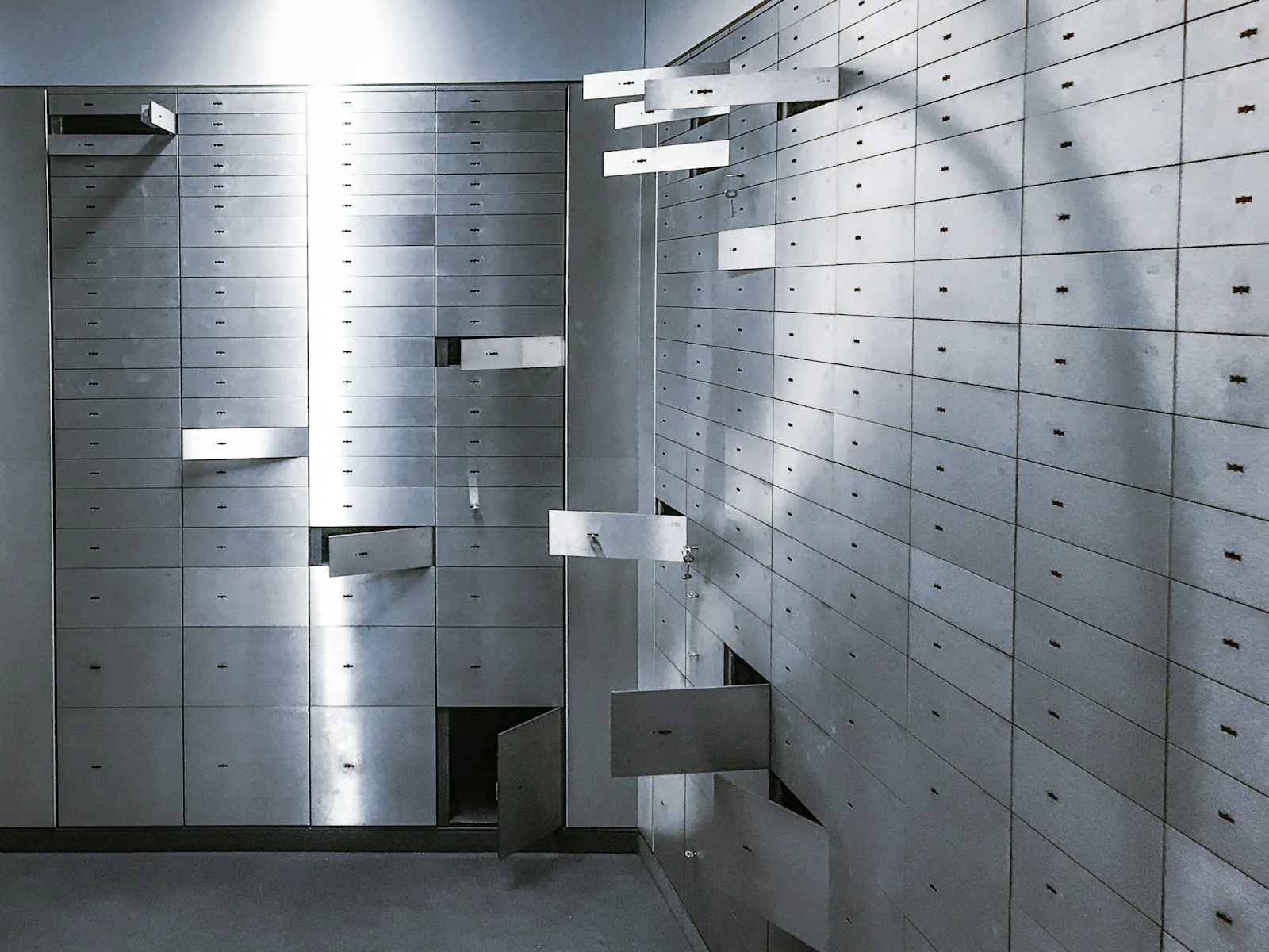 Rows of steel safe-deposit boxes in a vault, several drawers pulled open